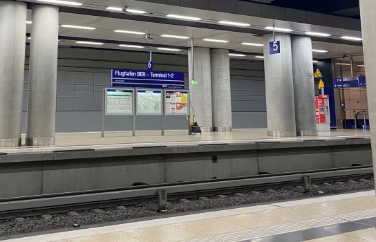 Bahnhof Flughafen BER mit Gleisen und Schild „Terminal 1-2“